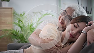 Affectionate loving senior mother comforting adult daughter taking peaceful nap on couch at home