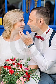 Affectionate mature couple in love embrace close to one another. Man touches woman's chin