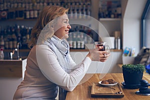 Affectionate mature woman sitting in cafe with cup of tea