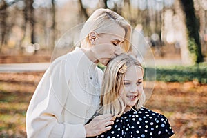 Affectionate Moment Between Mother and Daughter Outdoors. A tender scene of a mother kissing her daughter on the head in