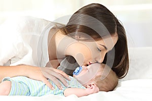 Affectionate mother kissing her baby sleeping photo
