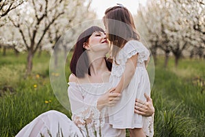 Affectionate mother kissing and hugging daughter at garden