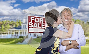 Affectionate Senior Chinese Couple In Front of House and Sign