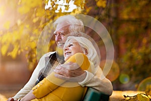 Affectionate senior couple on bench in autumn park