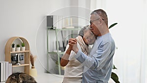 Affectionate senior couple dancing in living room, enjoying retired life and spending free time together at home