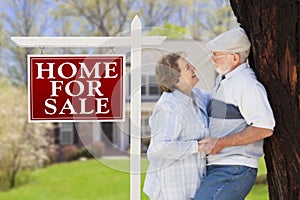 Affectionate Senior Couple Front of For Sale Sign and House