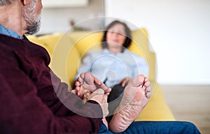 Affectionate senior couple in love sitting on sofa indoors at home, relaxing.