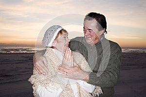 Affectionate senior couple in sweaters on beach