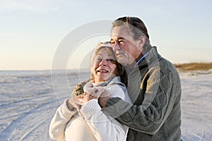 Affectionate senior couple in sweaters on beach photo