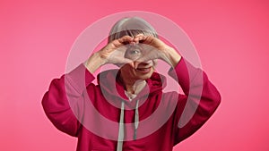 Affectionate Senior Lady in Rosy Hoodie Forming Heart Shape