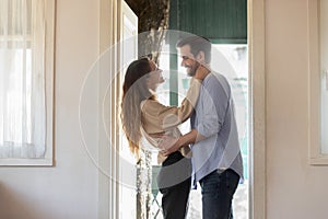 Affectionate wife embracing smiling husband meeting at house door