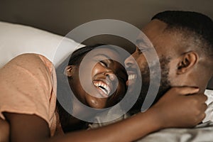 Affectionate young African American couple laughing together in bed