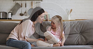 Affectionate young baby sitter nanny talking to little kid girl.