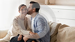 Affectionate young bearded man kissing cheek of beloved smiling girlfriend.