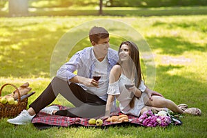 Affectionate young couple celebrating anniversary with wine on picnic in park