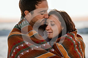 Affectionate young couple wrapped in a blanket at the beach