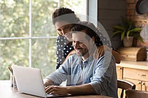 Affectionate young family couple using computer at home.