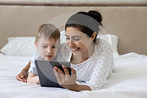 Affectionate young indian mother using tablet with little son.