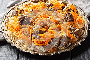 Afghan national dish Kabuli Pulao rice pilaf with lamb and raisin, carrot, nut, spices closeup on the plate. Horizontal