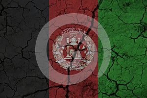 Afghanistan flag on the background texture of cracked earth. The concept of design solutions