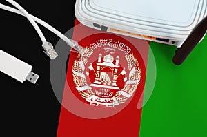 Afghanistan flag depicted on table with internet rj45 cable, wireless usb wifi adapter and router. Internet connection concept