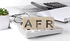 AFR written on a wooden cube on keyboard with office tools