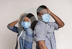 Afraid Black Couple Wearing Protective Masks And Holding Head With Hand