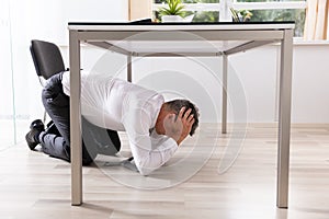 Afraid Businessman Hiding Under Table