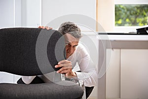 Afraid Businessman Peeking Behind Chair