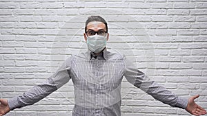 Afraid Caucasian young businessman with brown hair in black glasses in a checkered shirt in protective medical mask on face