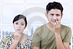 Afraid couple biting nails in apartment