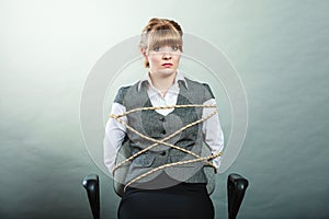 Afraid kidnapped woman tied with rope to chair.