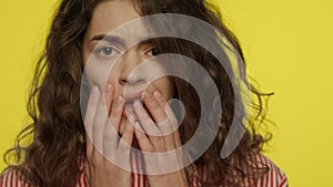 Afraid woman face with open mouth touching face with hands on yellow background