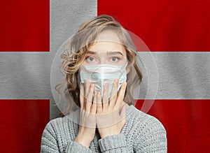 Afraid woman in medical mask on Danish flag background. Flu epidemic and domestic violence in Denmark concept