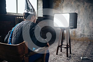 Afraided man in aluminum foil helmet sits in chair