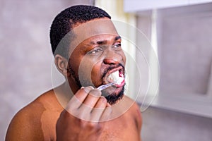 africa man toothbrush in bathroom looking at mirror