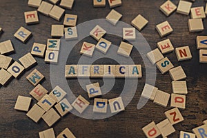 Africa - one of the seven continents. Colorful wooden letters creating the word AFRICA. Dark wooden table as a