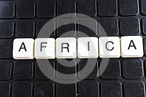 Africa title text word crossword. Alphabet letter blocks game texture background. White alphabetical letters on black