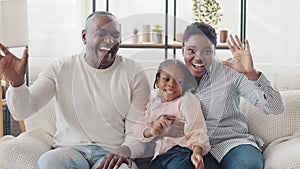 African afro family happy parents and little black child girl sitting at home sofa laughing loudly sincerely smiling