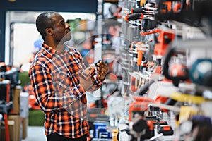 African americam man buying modern electric drill while standing in tool. Hardware construction site objects concept