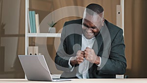 African American 60s businessman mature man boss in office has work break listen music with laptop singing song dancing