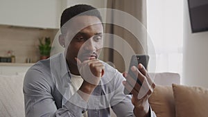 African-american adult man thinking and typing a reply with smile on his smartphone