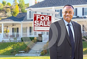 African American Agent In Front of Home For Sale Sign