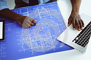 African american architect working with computer and blueprints in office