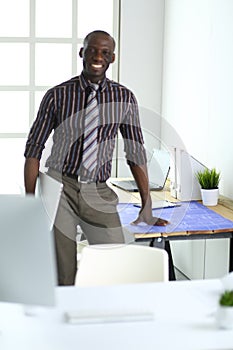 African american architect working with computer and blueprints in office