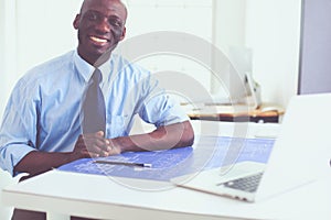 African american architect working with computer and blueprints in office
