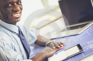 African american architect working with computer and blueprints in office