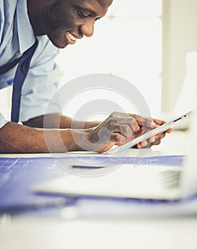 African american architect working with computer and blueprints in office