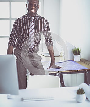 African american architect working with computer and blueprints in office