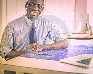 African american architect working with computer and blueprints in office